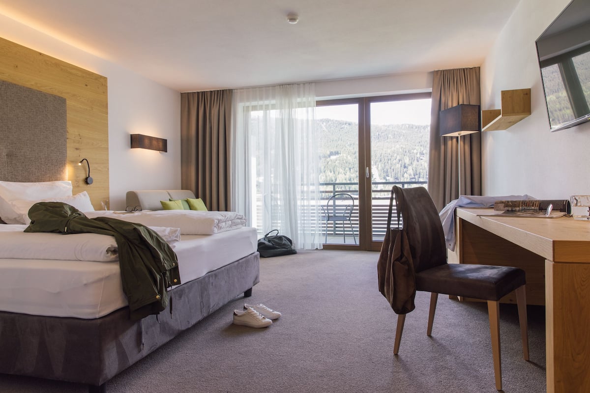 Ein Hotelzimmer mit Bett, Schreibtisch, Stuhl und Blick ins Freie.