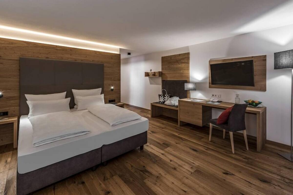 Ein modernes Hotelzimmer mit einem großen Bett, einem Schreibtisch und einem Stuhl.