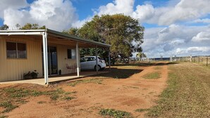 A single-story building with a covered porch and a car parked in front. - Farmstay cabins in Western Australia, close to highway. (Northampton)