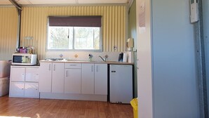 A compact kitchen with a window, a microwave, a sink, and a refrigerator. - Farmstay cabins in Western Australia, close to highway. (Northampton)