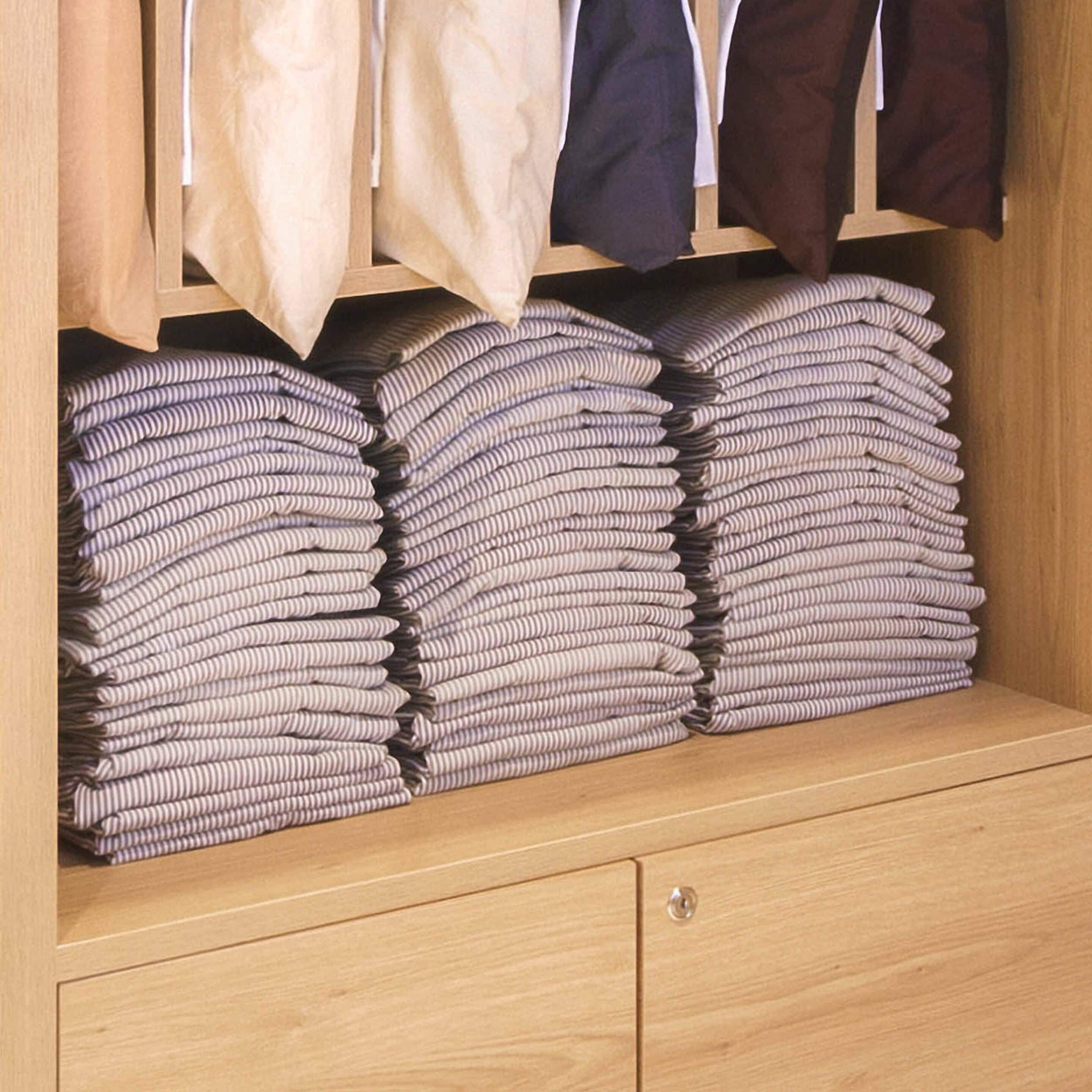 Ein Holzkleiderschrank mit mehreren Einlegeböden, der gefaltete Kleidung beherbergt, und einer Kleiderstange darüber mit verschiedenen Kleidungsstücken.