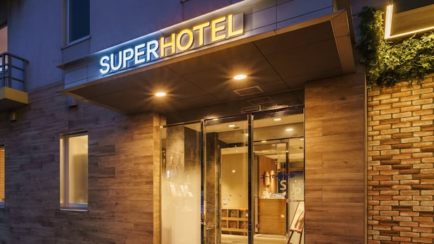 A hotel entrance with a modern design, featuring a glass door and a sign that reads "SuperHotel". - Super Hotel Tokyo JR Kamata Nishiguchi (Tokyo)