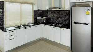 Une cuisine moderne avec des meubles blancs, un réfrigérateur en acier inoxydable, un four à micro-ondes et une cuisinière à gaz.