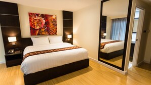 Une chambre d’hôtel avec un grand lit, une table de chevet avec une lampe, un tableau accroché au mur et un miroir.