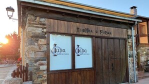 En rustik bygning med stenvægge og trædøre, med teksten "Tienda U Forra".
