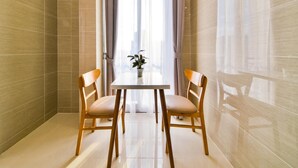 A room with a tiled floor, a table with two chairs, and a window with sheer curtains.