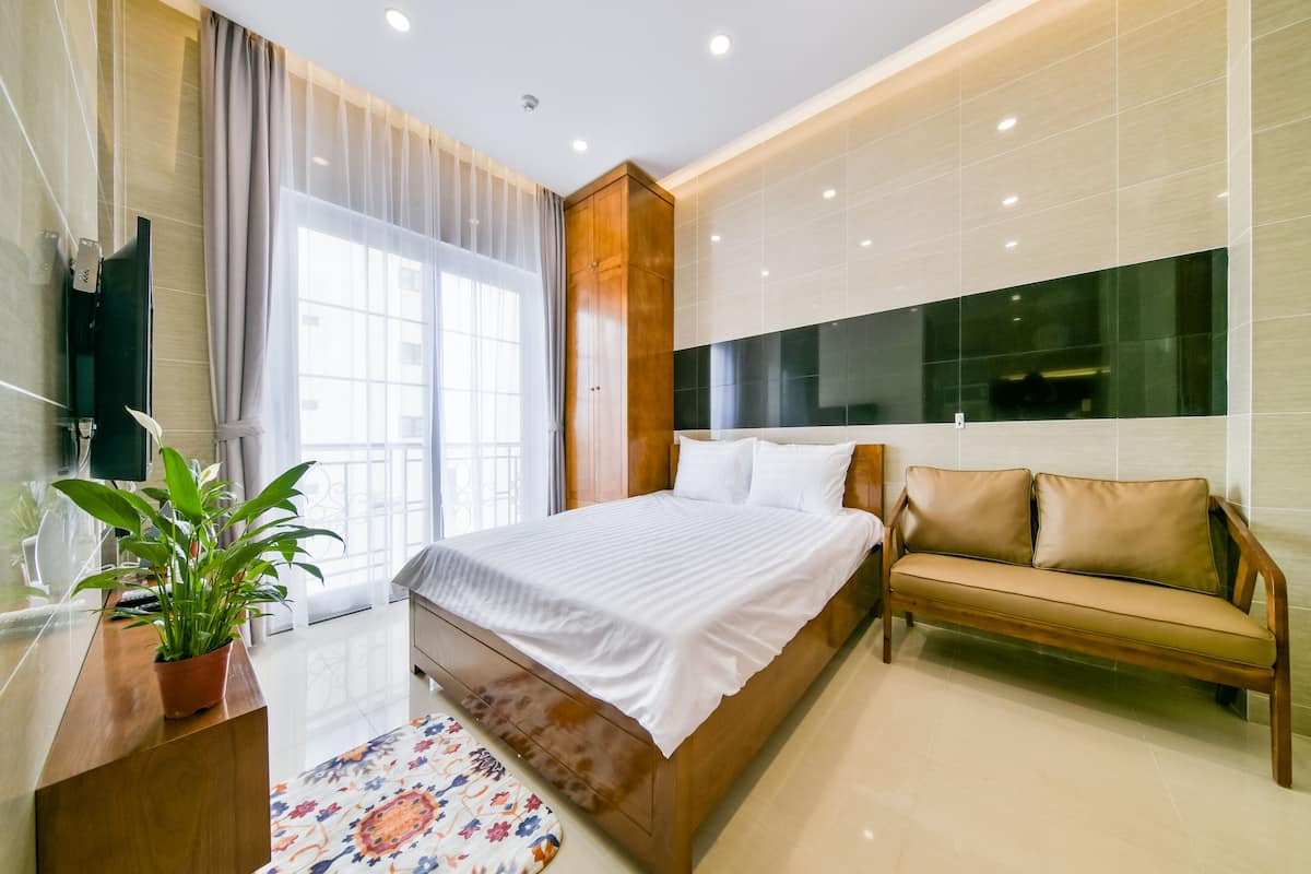 A modern bedroom with a large bed, a wooden bench, and a potted plant.