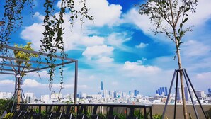 A rooftop terrace with a view of a city skyline, including a prominent skyscraper.