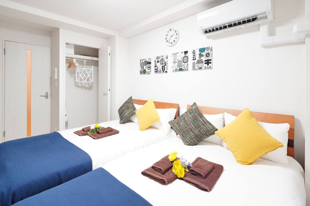 Une chambre d’hôtel avec deux lits, une armoire, une horloge et des œuvres d’art murales.
