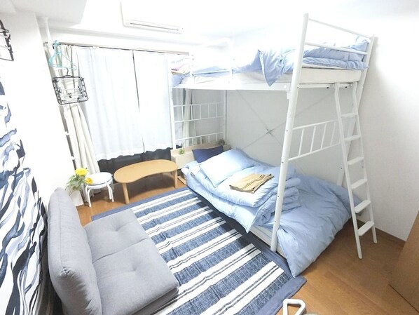 A bunk bed room with a desk, chair, and a small table with a plant.