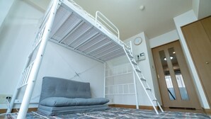 A bunk bed with a grey mattress and a ladder, a bedside table, a wall clock, and a door to the right. - Liv City Shinjuku Ⅱ 504 (Tokyo)