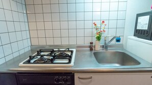 A kitchen with a gas stove, a sink, and a dishwasher. - Liv City Shinjuku Ⅱ 504 (Tokyo)