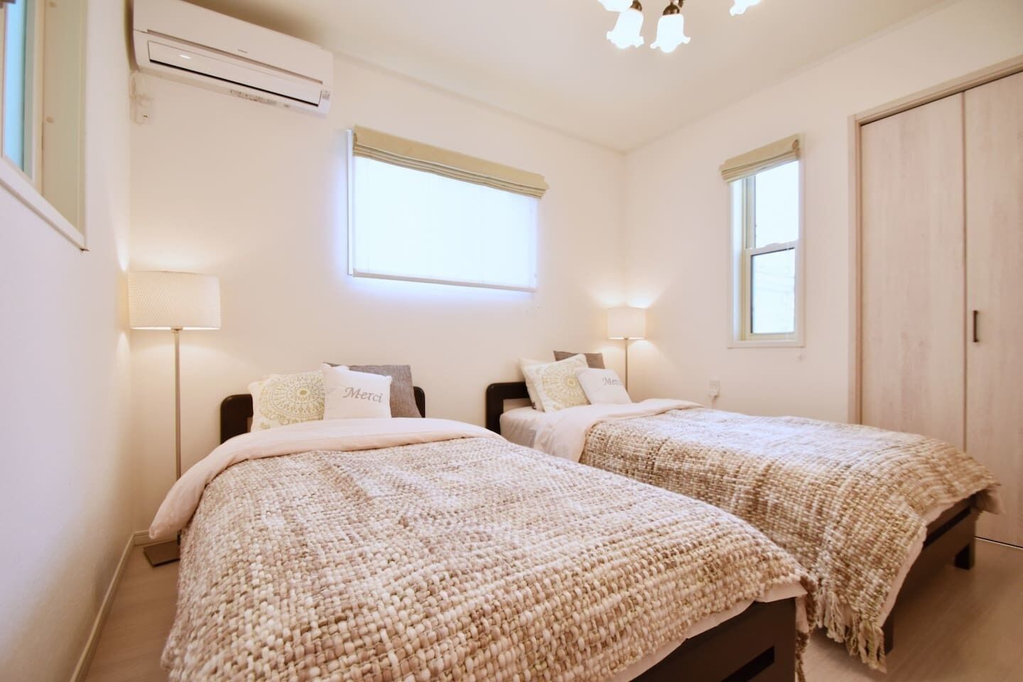 A bedroom with two beds, a ceiling fan, and a window.