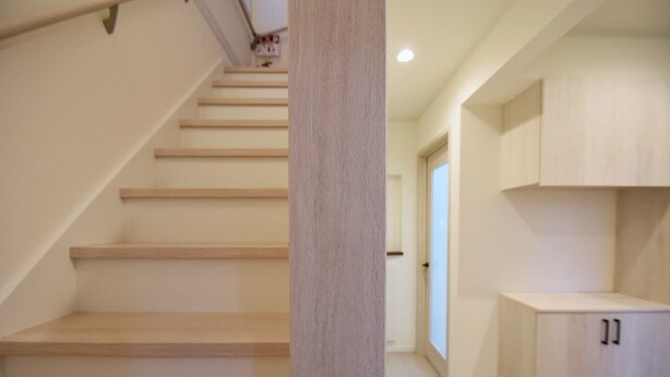 Eine Treppe führt zu einer Zwischenebene mit einer hellen Wand und einer Tür im Hintergrund.