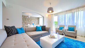 A modern living room with a sectional sofa, two armchairs, a coffee table, and a stone wall in the background. - Villa Vinodol (Kvarner - Novi Vinodolski) (Novi Vinodolski)