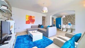 A modern living room with a blue shag rug, a grey sofa, and a white coffee table. There is a stone wall and a blue accent wall in the background. - Villa Vinodol (Kvarner - Novi Vinodolski) (Novi Vinodolski)