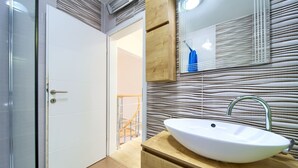 A modern bathroom with a white sink, wooden vanity, and a mirror with a wooden frame. - Villa Vinodol (Kvarner - Novi Vinodolski) (Novi Vinodolski)