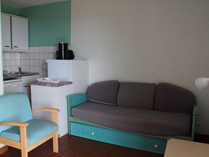 A compact kitchen with a white countertop, a black coffee maker, and a teal sofa. - Small Studio No. 5 with Ocean View (Bormes-les-Mimosas)