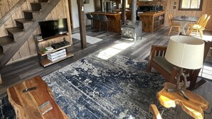 Ein großzügiger Wohnbereich mit einer breiten Holztreppe, einer Küche mit modernen Geräten und einer gemütlichen Sitzecke mit Teppich und Holzmöbeln.