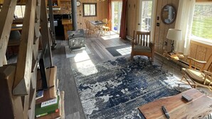 Ein geräumiges Zimmer mit hohen Decken, Holzbalken, einem großen Fenster und einem rustikalen Holzboden.
