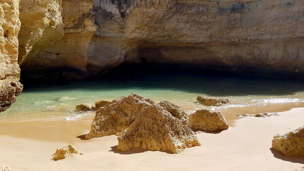 Una playa con agua turquesa cristalina, una orilla de arena y formaciones rocosas.