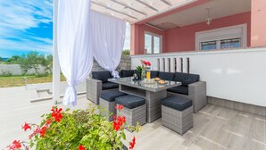 An outdoor patio with wicker furniture, a glass table, and a white curtain. - Villa Maris (Benkovac)