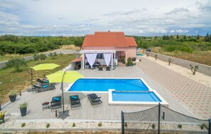 Relax by the pool surrounded by lush greenery and a scenic hillside view.