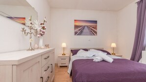 A bedroom with a bed, two bedside tables, a dresser, a mirror, and a painting of a sunset over a bridge. - Villa Maris (Benkovac)