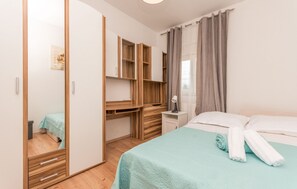 Relax in a clean and modern space with a comfortable bed, wooden shelves, and a large mirror.