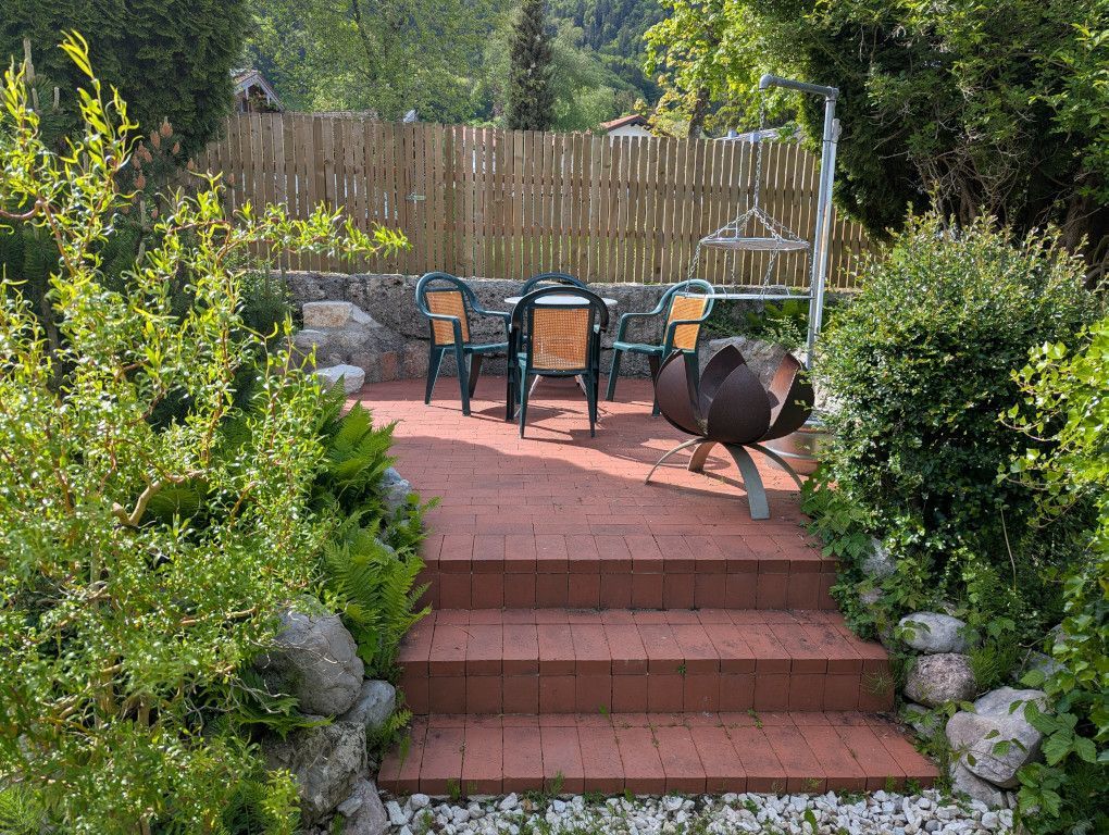 Eine Terrasse mit Tisch, Stühlen, einem Grill und Treppen zu einem Holzboden.