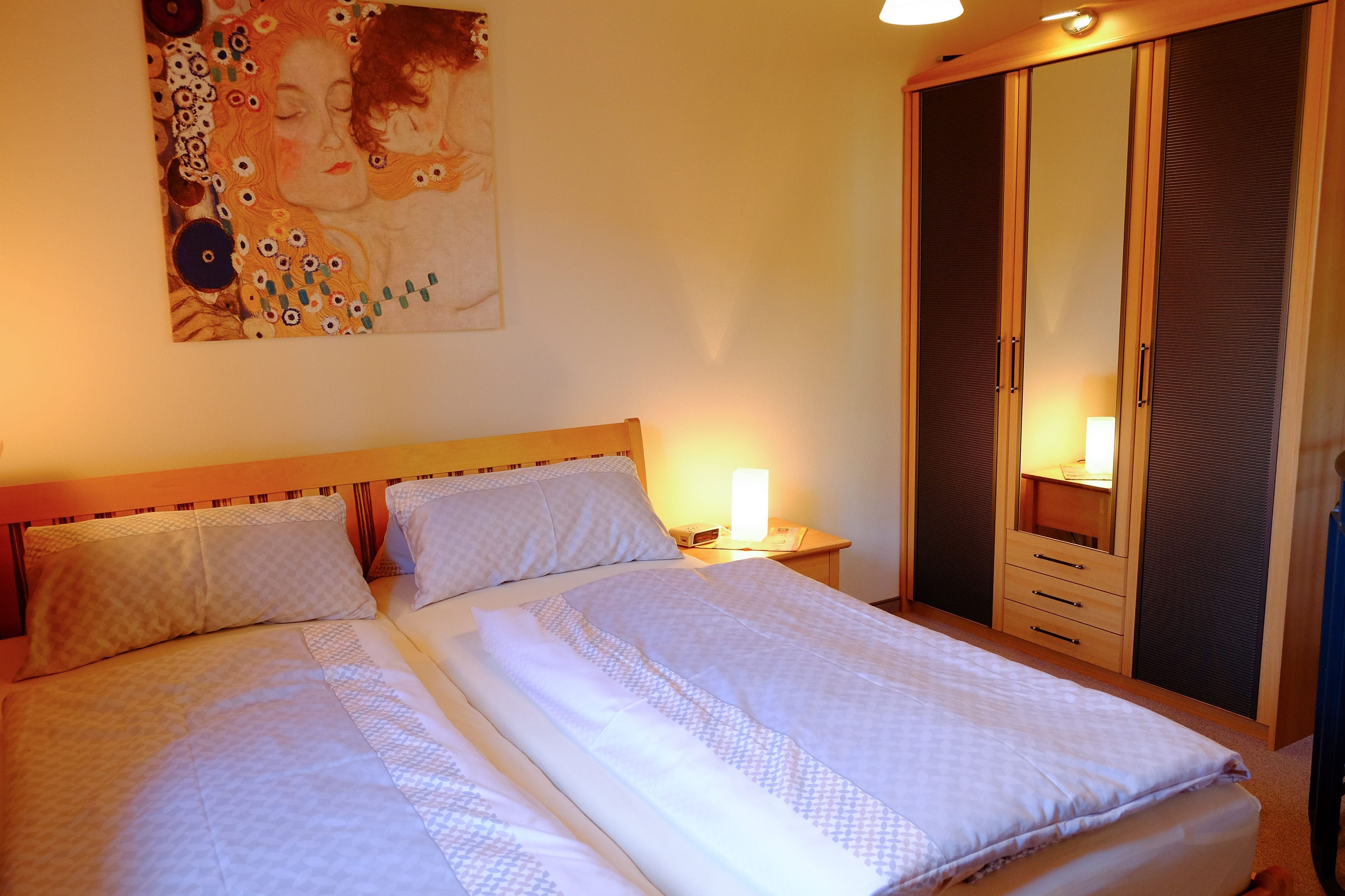 Un lit double avec une tête de lit, une table de chevet avec une lampe et une armoire avec un miroir.