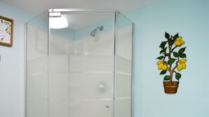 Ein Badezimmer mit einer gläsernen Duschkabine, einer Toilette und einer am Wand befestigten Pflanze.