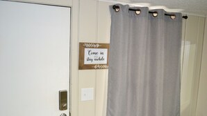 Ein Zimmer mit geschlossener Tür, einem Lichtschalter und einem Schild an der Wand mit der Aufschrift 'Hereinkommen und eine Weile bleiben.'