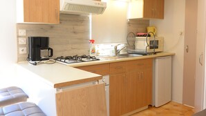 Una cocina compacta con armarios de madera, estufa a gas, cafetera y lavavajillas.