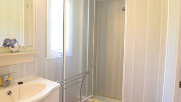 A bathroom with a sink, mirror, and shower.