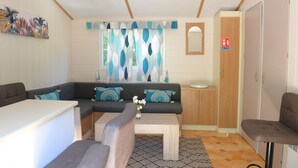 Un espacio habitable compacto con sofá, una pequeña mesa de comedor, una mesita de centro, un armario y un área de baño con inodoro y lavabo.