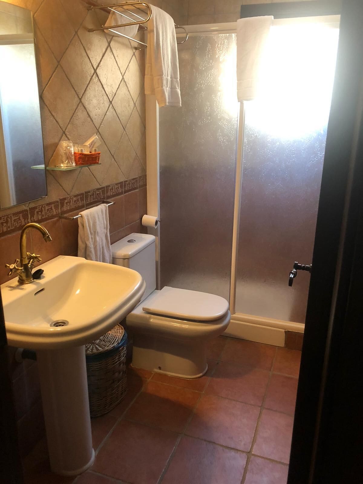 Et badeværelse med håndvask, toilet og bruser.