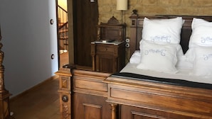 Un dormitorio con cama de madera, mesita de noche, cómoda y pared de ladrillo.