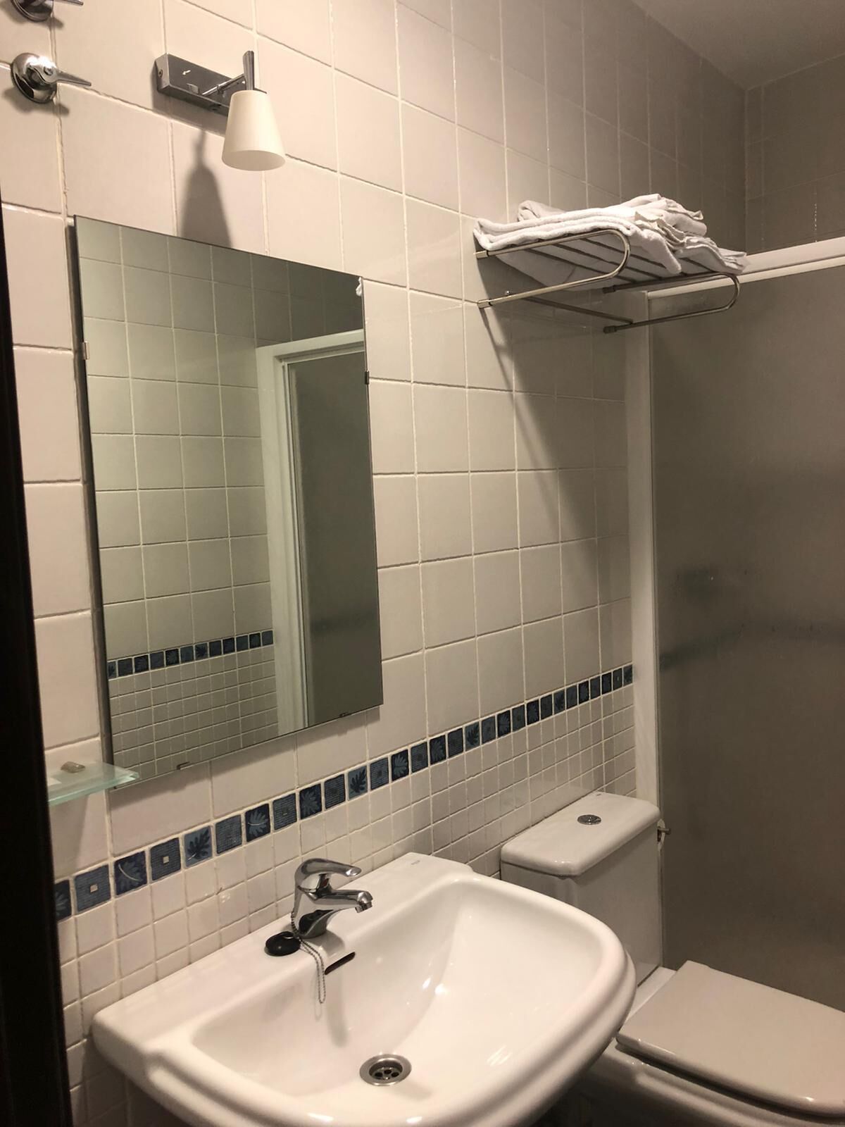 A bathroom with a white sink, a toilet, a towel rack, and a mirror.