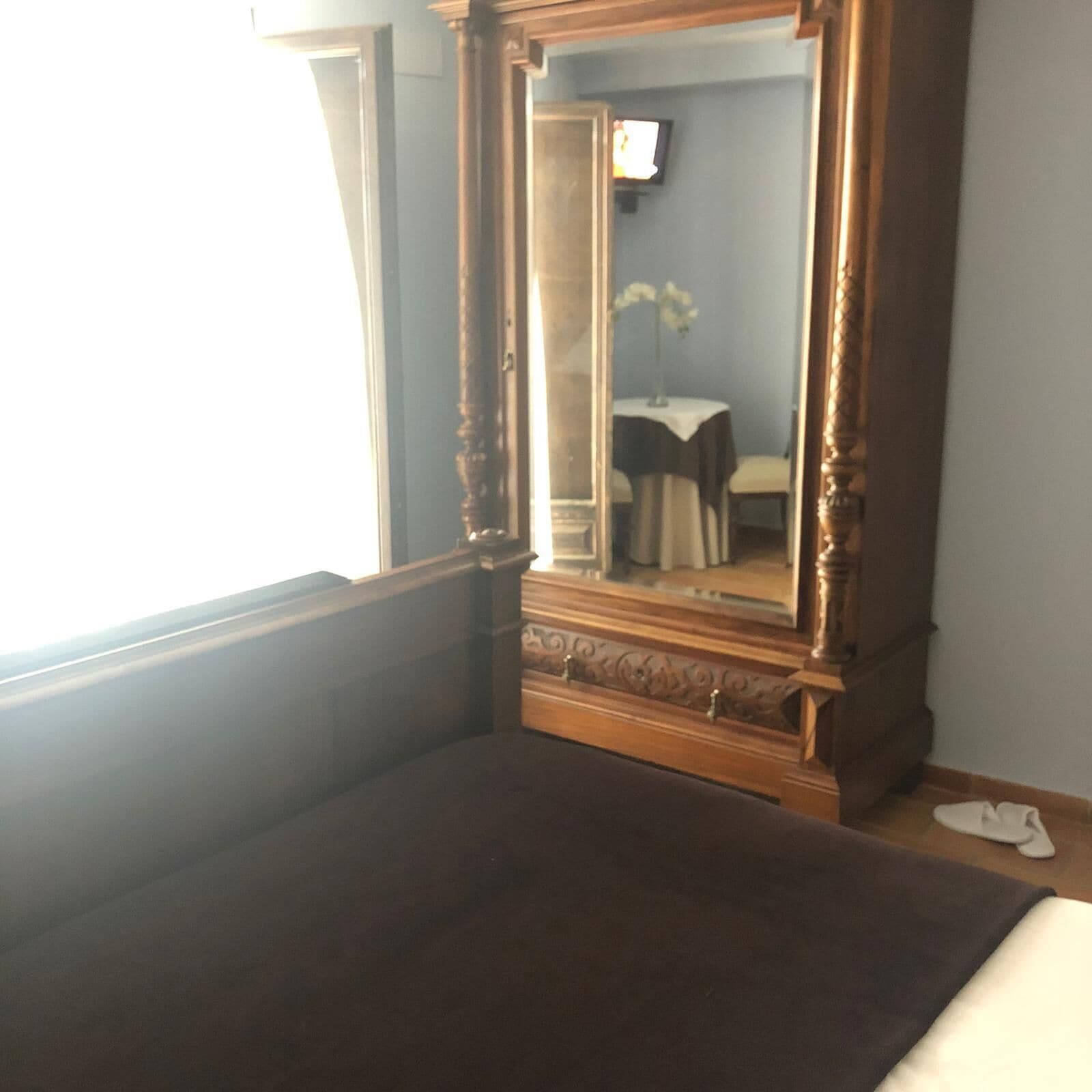 Une chambre avec un grand miroir, un lit et une petite table avec une chaise.