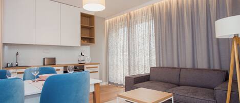 Una sala de estar moderna con un sofá, una mesa de comedor con sillas y una cocina al fondo.