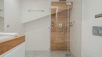 A modern bathroom with a glass shower enclosure, a wooden vanity, and a white sink.