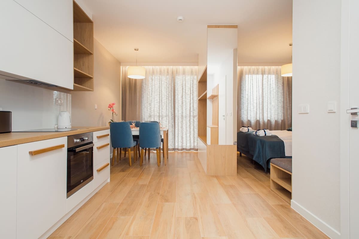 A modern kitchen with a dining area, a built-in oven, and a seating area with a bed.