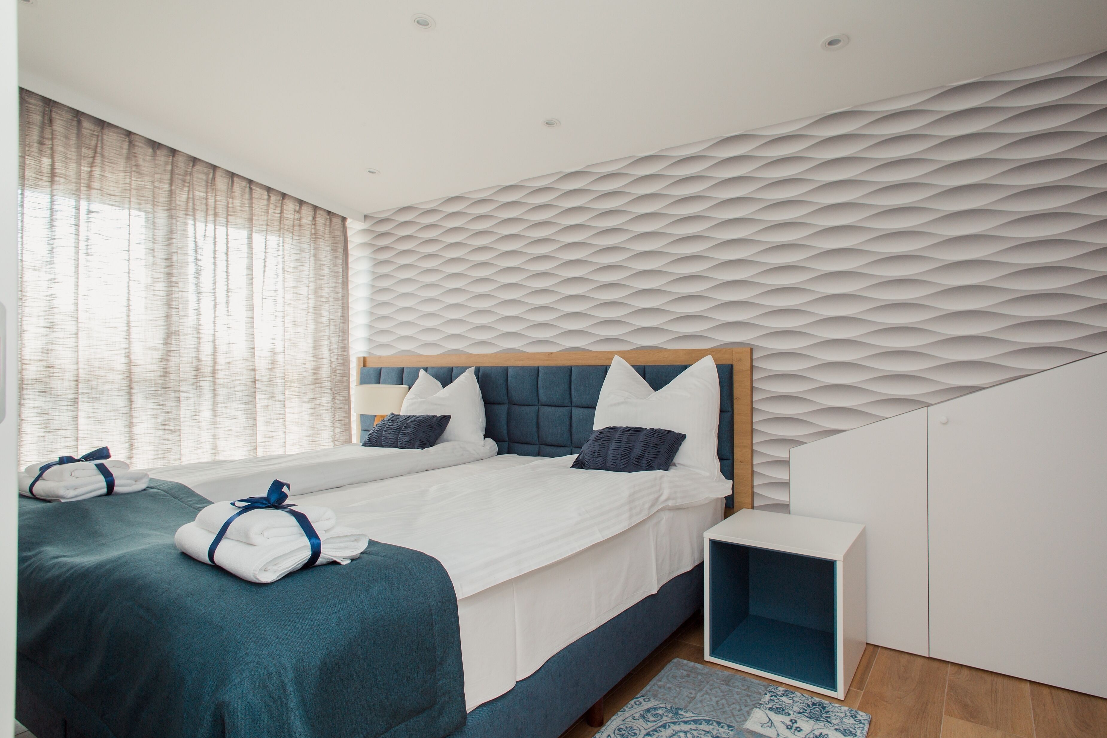 Una habitación de hotel moderna con una cama grande, un cabecero con diseño geométrico y un armario empotrado.