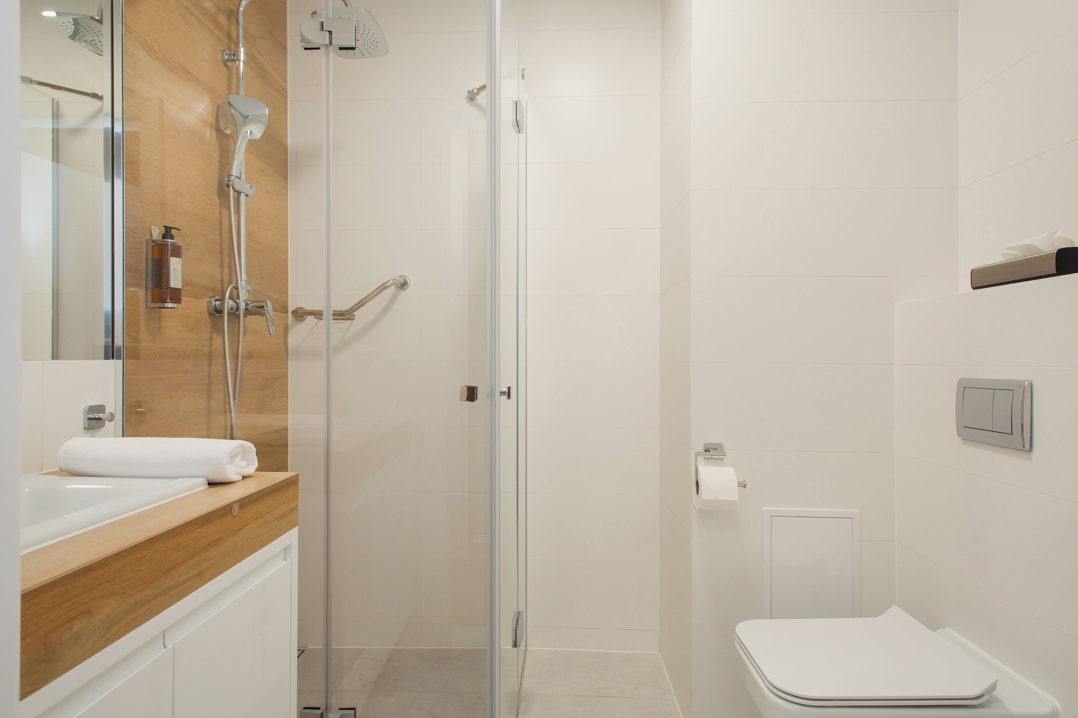 A modern bathroom with a glass-enclosed shower, a white toilet, and a wooden vanity with a sink.