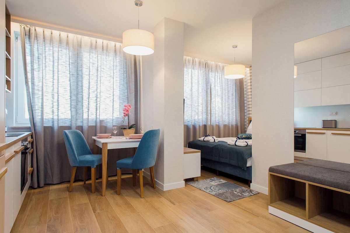 A modern, compact living space with a dining area, kitchenette, and a cozy sleeping area.