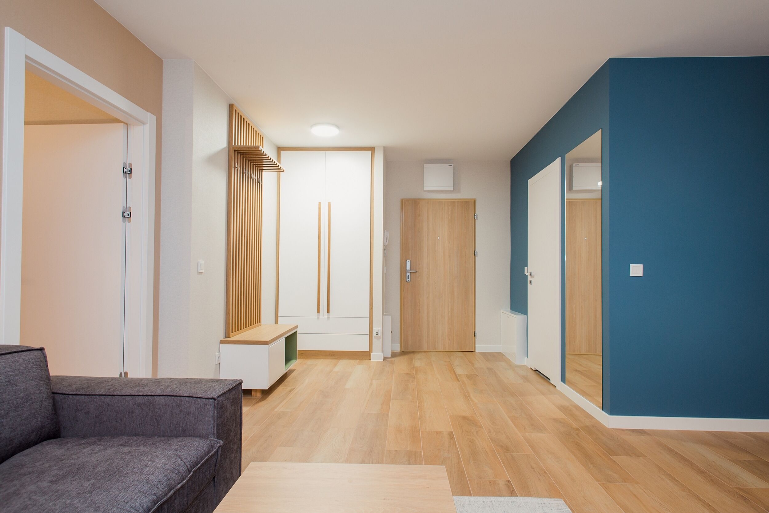 Una sala de estar moderna con un sofá gris, suelo de madera y una pared azul de acento.