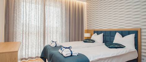 A hotel room with a large bed, two bedside tables, and a wooden desk.
