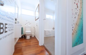 Enjoy a refreshing bathroom with a bathtub, framed artwork, and a window offering a view of the beach.