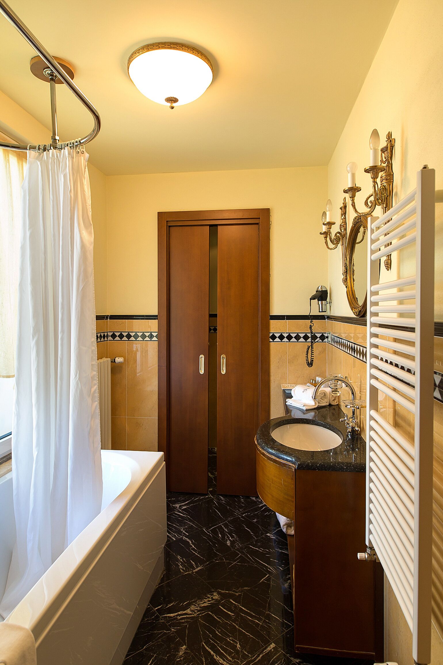 Un baño con bañera, lavamanos, espejo y toallero.